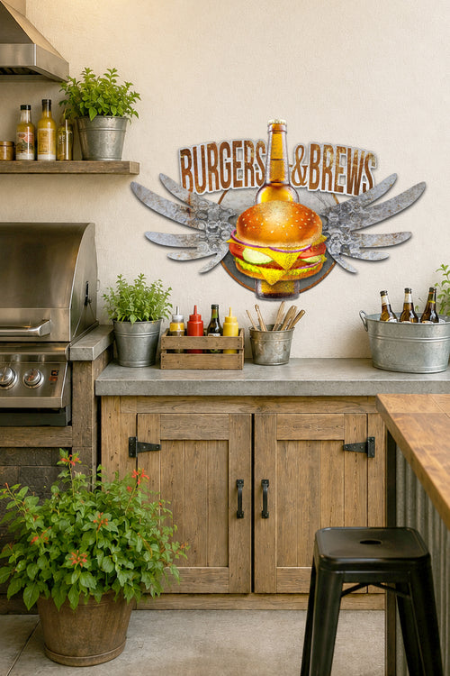 A rustic kitchen or bar wall decor sign reading 'BURGERS & BREWS' with a large burger and beer bottle motif, mounted above wooden cabinets in a styled interior scene with plants, bottles, and a stool.