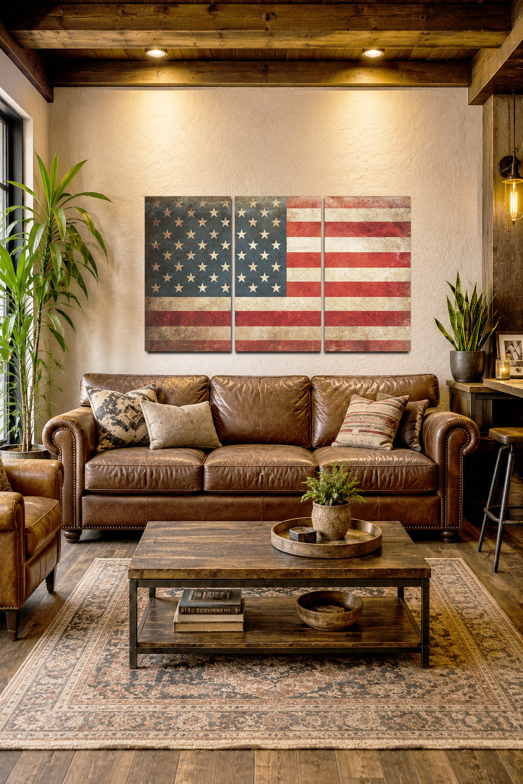 A rustic three-panel canvas wall art set depicting a distressed American flag, styled in a cozy living room above a brown leather sofa.