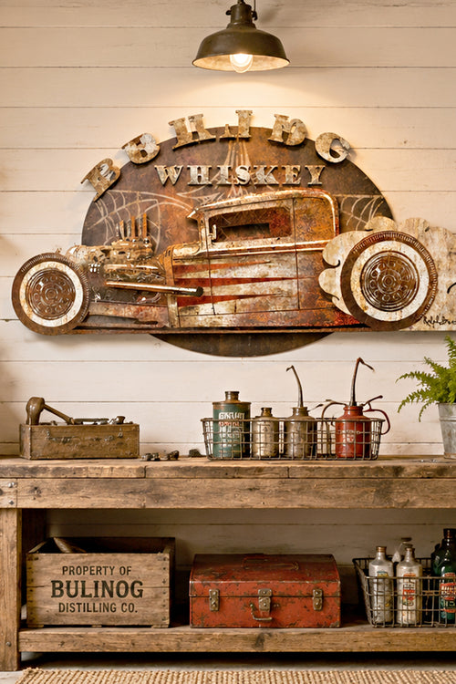 A rustic metal wall sign with a distressed hot rod truck design and the words 'Burnout Whiskey' and 'What a Life,' shown on a light beige background with decorative text above each sign.