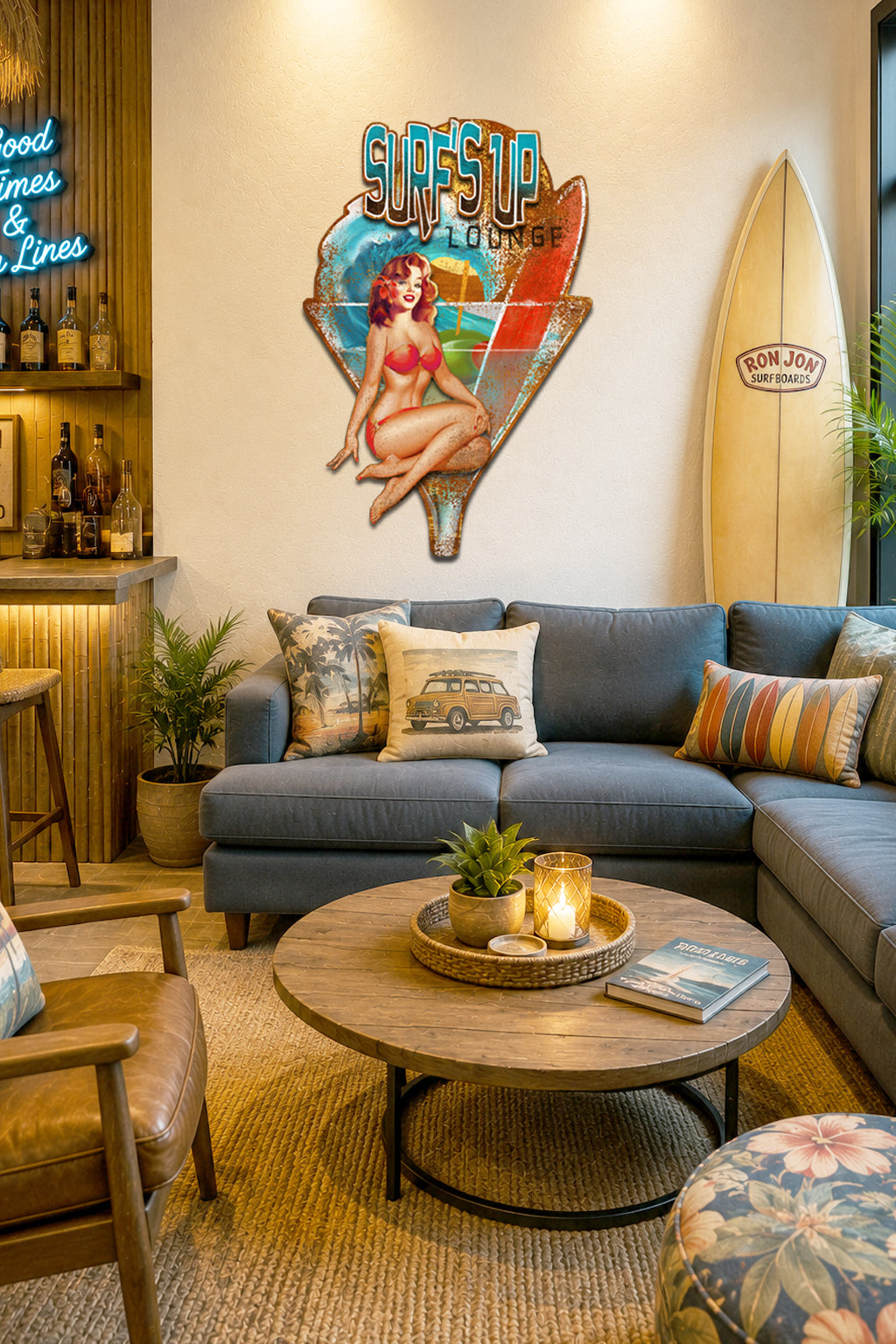 A styled living room corner featuring a blue sectional sofa with decorative pillows, a round wooden coffee table, a leather chair, and a large retro metal sign on the wall that reads 'Surf & Surf Lounge' with a pin-up illustration and a surfboard-shaped design.
