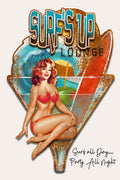 A vintage-style illustrated surf-themed sign or poster reading 'SURF'S UP LOUNGE' with a pin-up woman in red bikini seated on a red and blue surfboard shape, plus the text 'Surf all day.